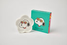 Flower-shaped ceramic trinket dish featuring a black-and-white beagle wearing rainbow heart sunglasses, paired with a teal gift box.