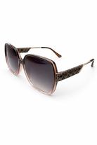 Sunglasses with brown gradient lenses and decorative metal frame on a white background