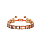 A bronze bracelet with geometric pattern, featuring orange and blue elements, and adjustable ends.