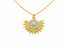 Gold necklace with a sunburst pendant featuring a central gemstone on a white background