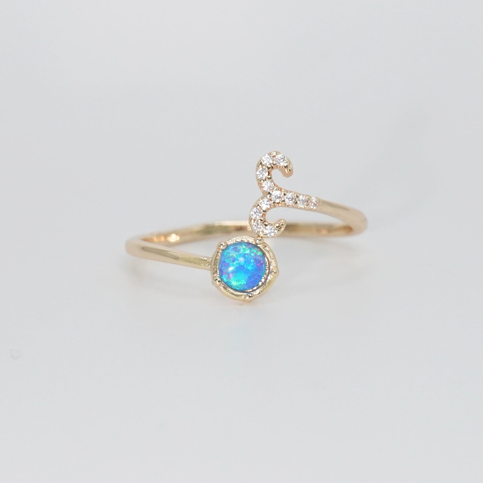 Aries Ring: Ram symbol with shimmering stones surrounding an opal, embodying fiery spirit.