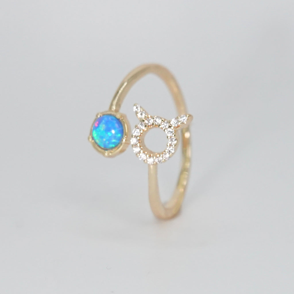 Taurus Ring: Bull symbol with shimmering stones surrounding an opal, epitome of stability.