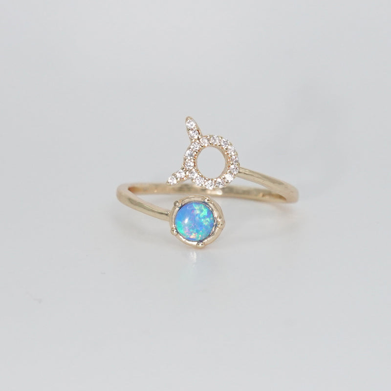 Taurus Ring: Bull symbol with shimmering stones surrounding an opal, epitome of stability.
