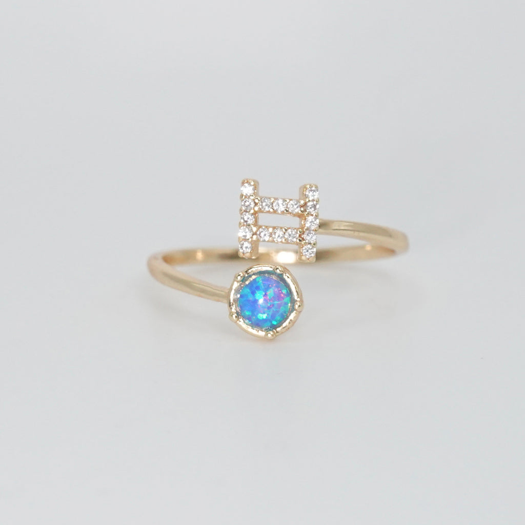 Gemini Ring: Twin symbols with shimmering stones surrounding an opal, symbolizing duality.