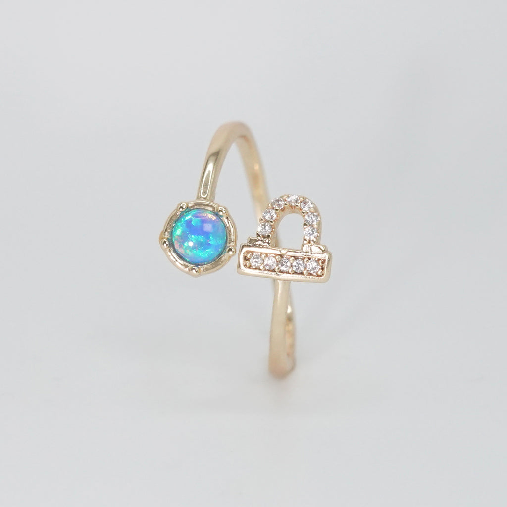  Libra Ring: Scales symbol with shimmering stones surrounding an opal, epitome of balance.