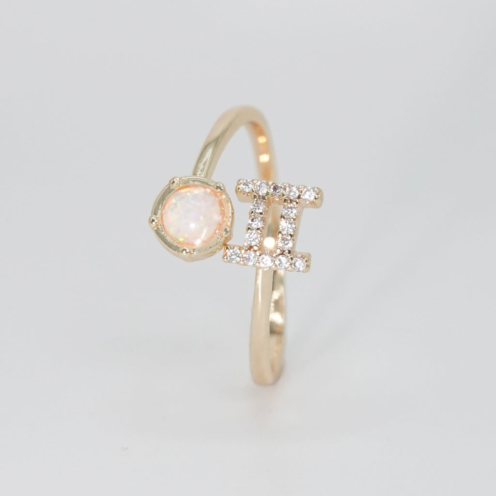 Gemini Ring: Twin symbols with shimmering stones surrounding an opal, symbolizing duality.