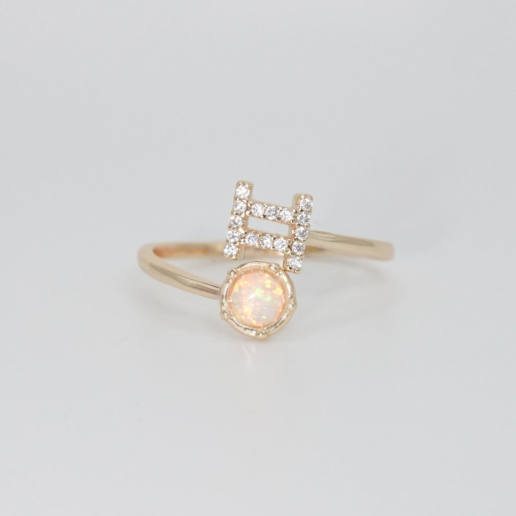 Gemini Ring: Twin symbols with shimmering stones surrounding an opal, symbolizing duality.