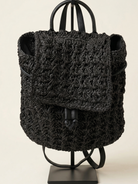 Black textured backpack on a stand against a beige background