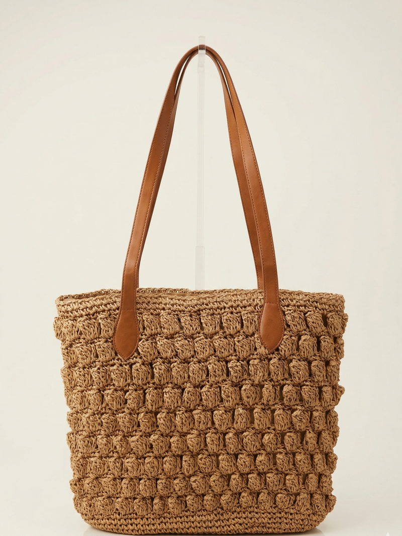 Brown woven tote bag with brown leather straps on a light beige background