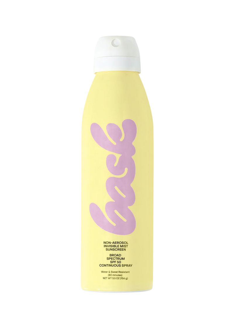 Hand holding Bask SPF 50 Sunscreen Spray, showing the spray function against a sunny beach scene.