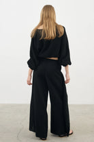 Siena Top displayed on a hanger, showcasing its wide sleeves and the unique V-shaped front drape with a hidden optional closure.