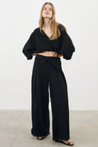 Siena Top displayed on a hanger, showcasing its wide sleeves and the unique V-shaped front drape with a hidden optional closure.
