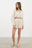 Siena Top displayed on a hanger, showcasing its wide sleeves and the unique V-shaped front drape with a hidden optional closure.