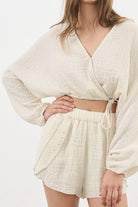 Siena Top displayed on a hanger, showcasing its wide sleeves and the unique V-shaped front drape with a hidden optional closure.