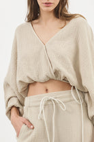 Siena Top displayed on a hanger, showcasing its wide sleeves and the unique V-shaped front drape with a hidden optional closure.