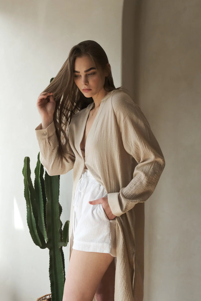 A woman wearing the Terra Shirt Dress, showcasing its relaxed silhouette, button-down front, and waist tie, epitomizing casual comfort and style.