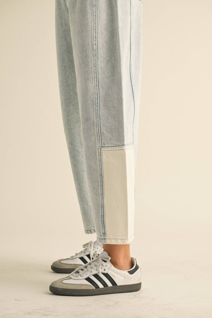 Model wearing light-wash wide-leg jeans with white contrast panels on the lower leg, styled with sneakers.