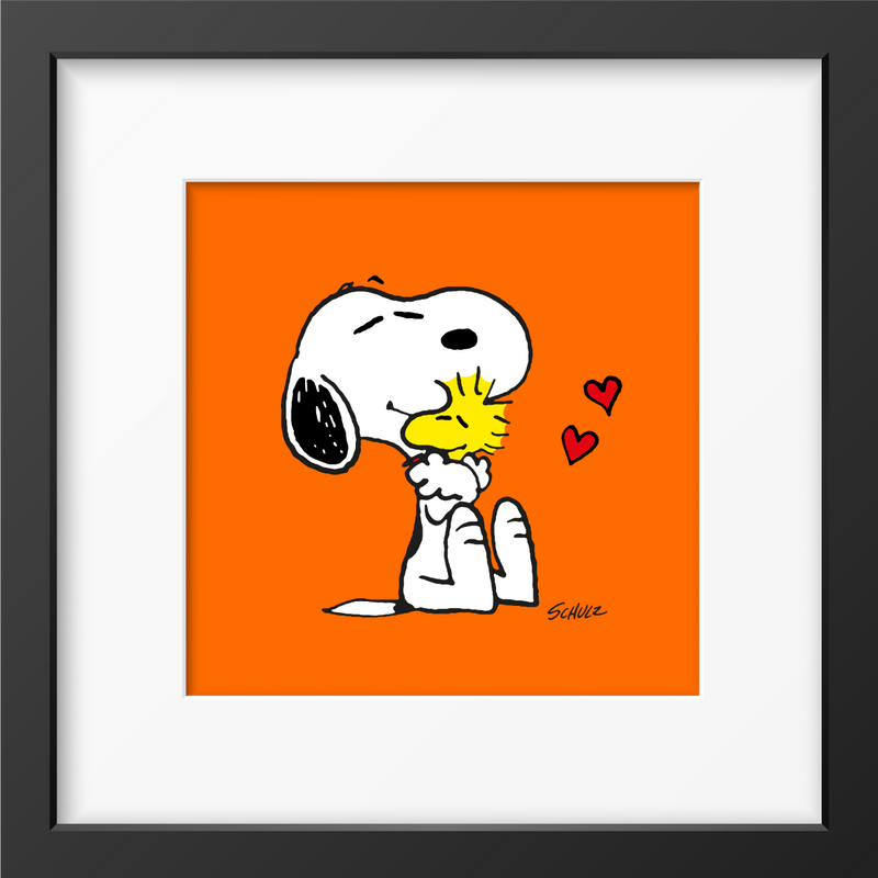 Framed artwork of Snoopy hugging Woodstock with red hearts, set against a bright orange background and framed in black.