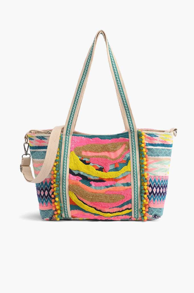 Multicolor embroidered crossbody bag with abstract beading, patterned sides, pom-pom trim, and detachable strap.