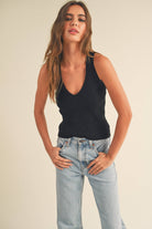 Model wearing a sleeveless ribbed knit top with deep V-neck and cross-back strap detail.