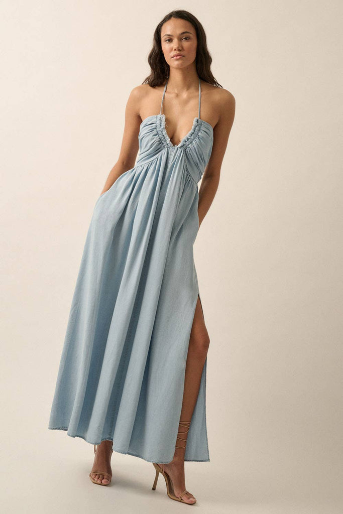 Woman wearing a light blue halter maxi dress with a plunging neckline, side slit, and flowy fit.