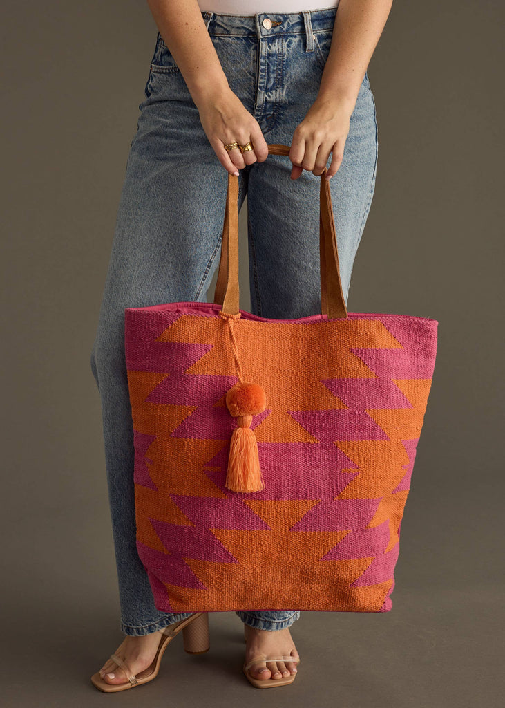 Bright pink and orange zigzag patterned tote bag with tassel charm and leather straps