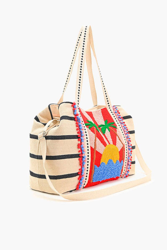 Beaded tote bag with sunset, palm tree, and ocean design, featuring black stripes, colorful pom-pom trim, and long handles.