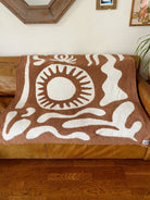Soft brown plush throw blanket with a sun and palm tree design, perfect for adding warmth and a stylish accent to any space.