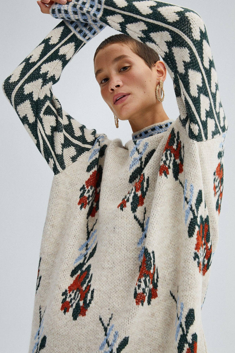 Woman wearing a Fair Isle floral knit sweater with long sleeves and mixed pattern detailing in red, green, and blue.
