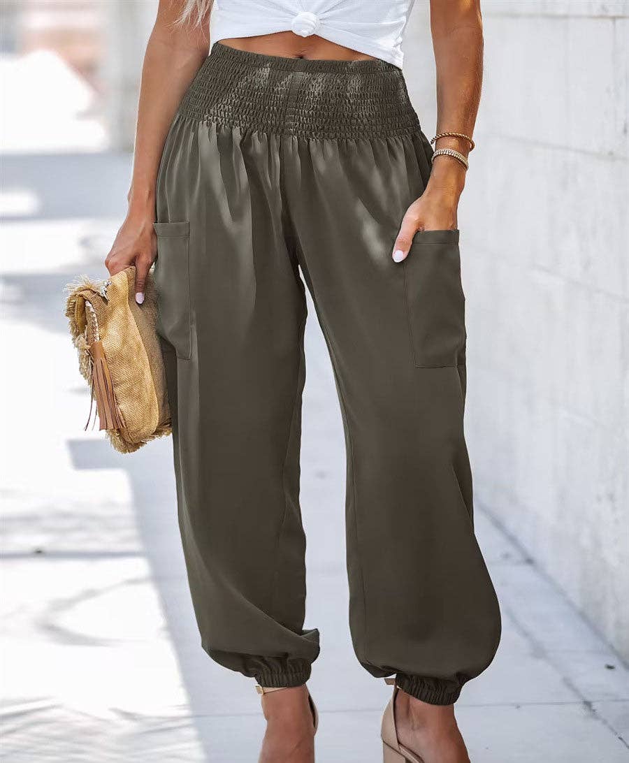Woman wearing Serenity High-Waist Comfort Pants in beige and olive colors, paired with a white crop top and heels, carrying a decorative clutch.