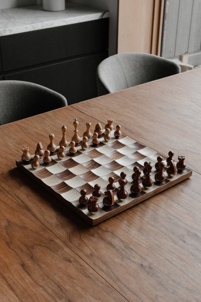 Modern wobble chess set with rounded-bottom wooden pieces and curved maple and walnut board.