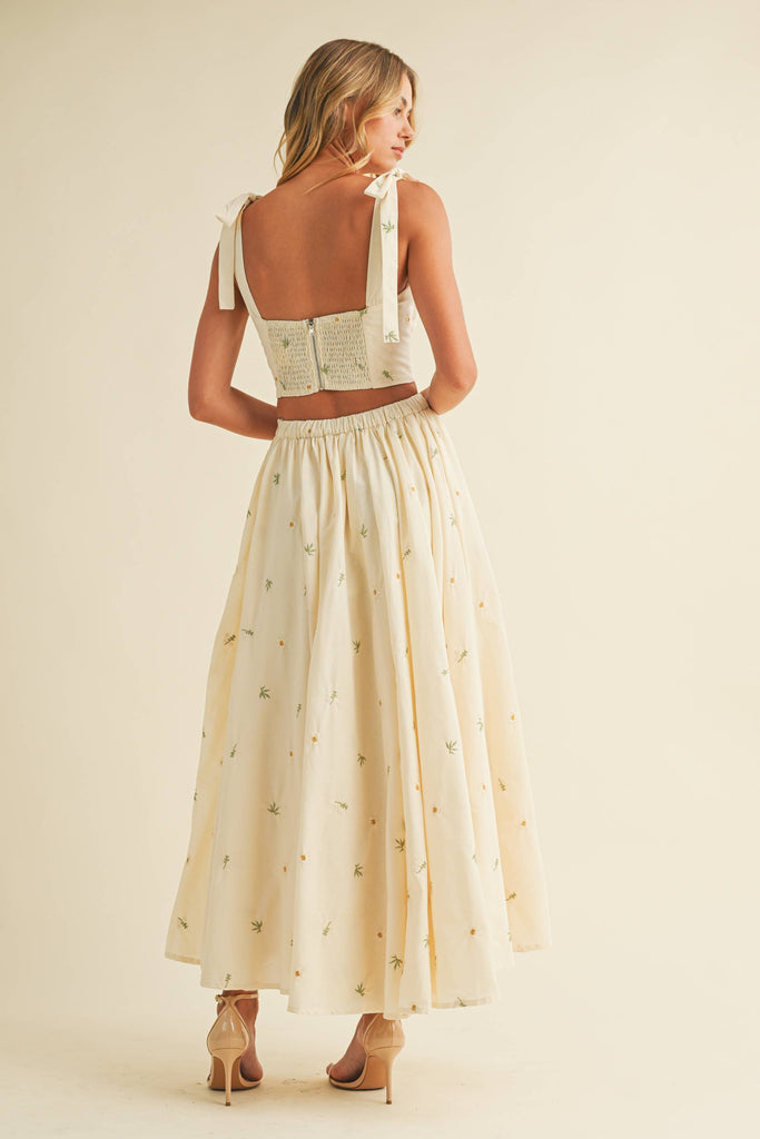 Light cream two-piece set with small floral embroidery, featuring bow-tie strap top and flowy maxi skirt