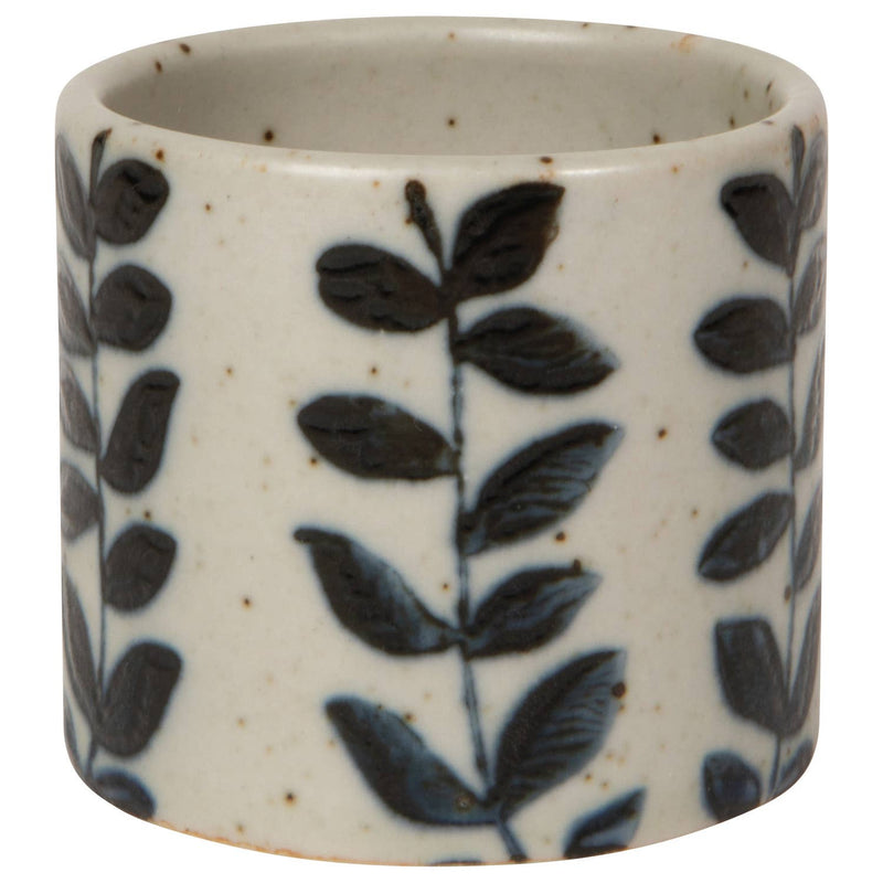Ceramic cup with black leaf pattern on a white background