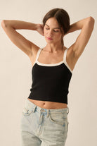 Black ribbed knit tank top with white trim on the straps and neckline, styled with light-wash denim jeans.
