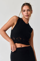 Woman wearing a black sleeveless crochet top and midi skirt set.