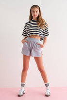 Close-up of a woman wearing gray elastic waist shorts with side zipper details.