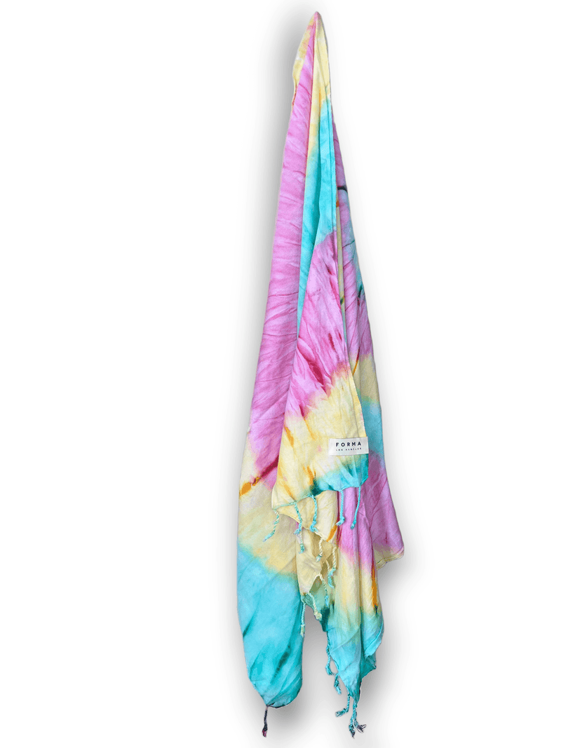A colorful set of Forma Towels from the Aura Collection, displayed as beach towels, home towels, and a shawl.