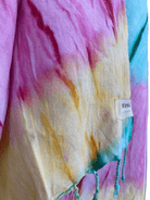 A colorful set of Forma Towels from the Aura Collection, displayed as beach towels, home towels, and a shawl.