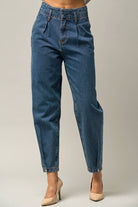  Model wearing high-waist balloon jeans with a relaxed silhouette and slightly tapered legs, paired with a casual graphic t-shirt and neutral heels.