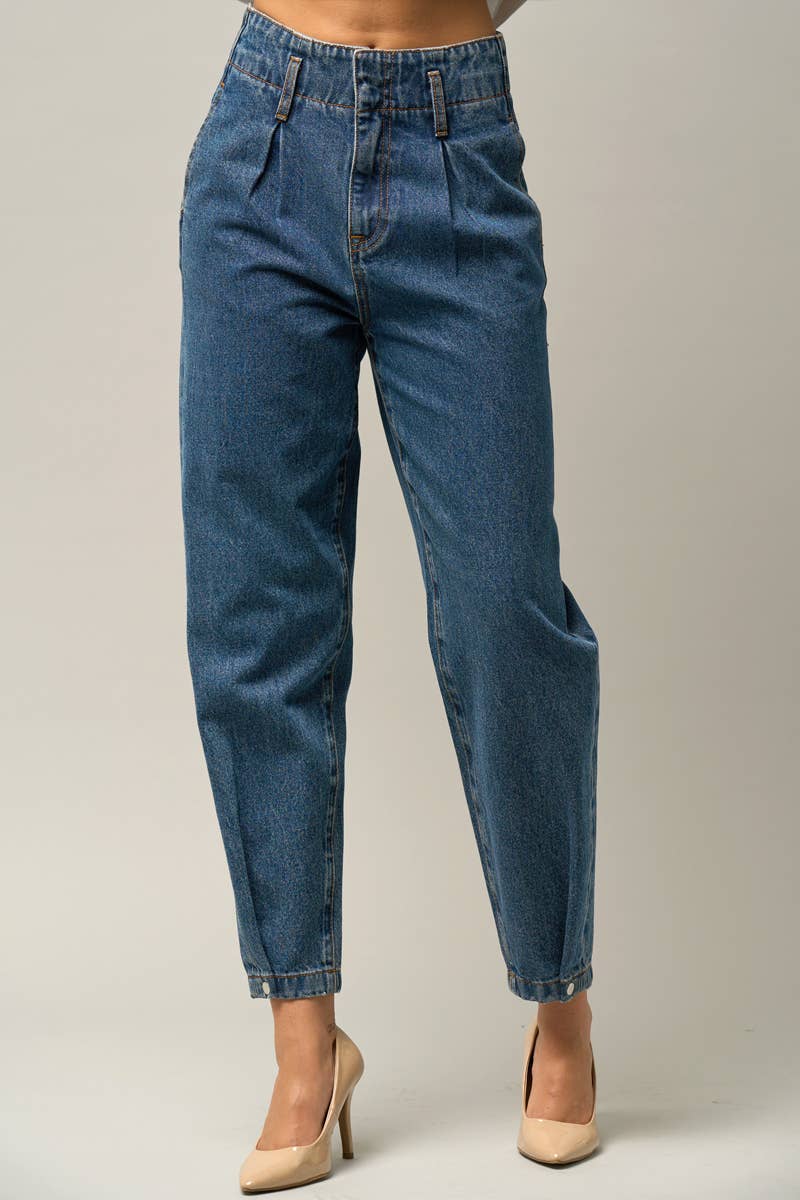  Model wearing high-waist balloon jeans with a relaxed silhouette and slightly tapered legs, paired with a casual graphic t-shirt and neutral heels.
