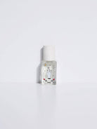 Maison Matine Avant l’Orage perfume bottle with celestial illustrations, placed among citrus fruits and sample vials on blue fabric