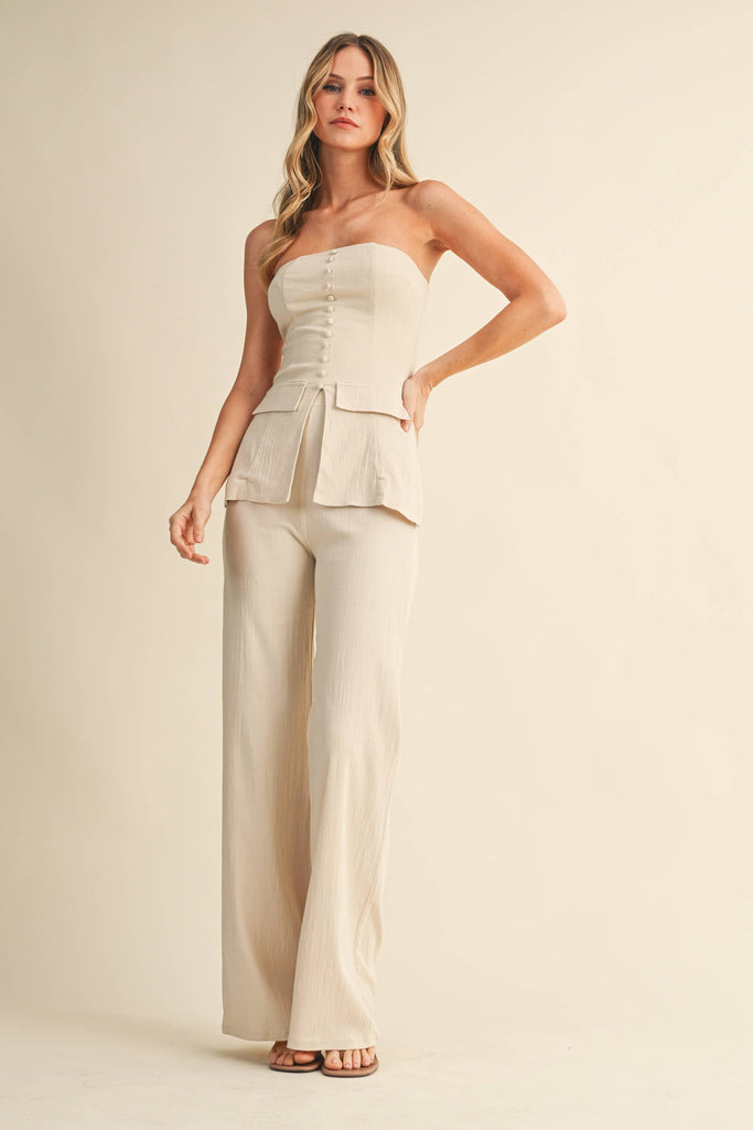 Woman wearing a strapless top and wide-leg pants on a beige background