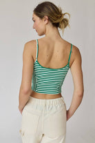 Woman wearing a green and white stripe rib knit tank top with thin straps and high-waisted beige shorts.