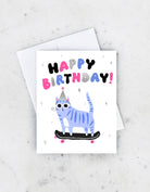 Birthday card with a blue cat wearing sunglasses and a party hat, riding a skateboard under “Happy Birthday” text.