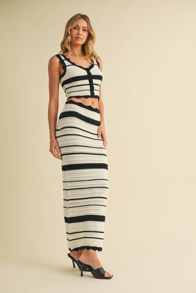 Woman wearing black and white striped crochet knit crop top and matching maxi skirt with scalloped trim