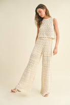 Model wearing cream-colored crochet wide-leg pants with intricate patterns and a high waist.