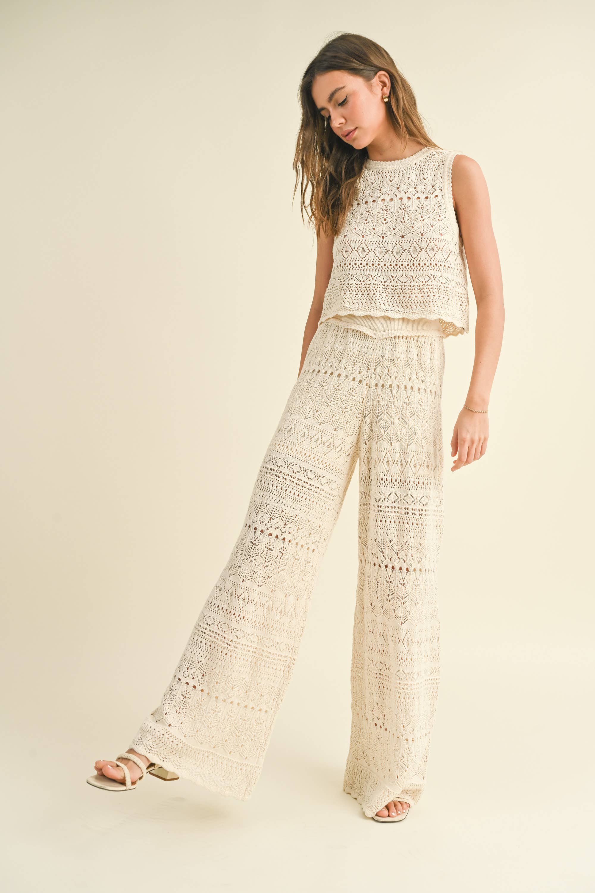 Model wearing cream-colored crochet wide-leg pants with intricate patterns and a high waist.