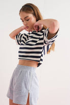 Close-up of a woman wearing gray elastic waist shorts with side zipper details.