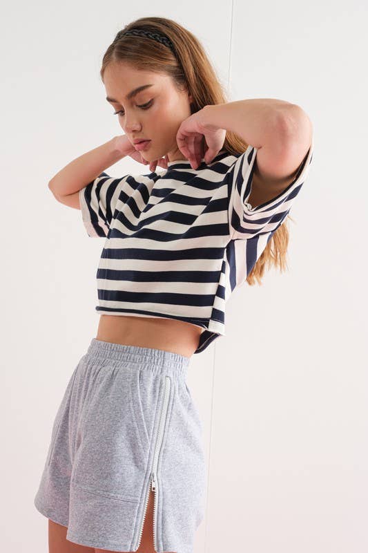 Close-up of a woman wearing gray elastic waist shorts with side zipper details.