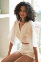 Stylish woman posing in a Bali Wrap Top with a V-neckline, front tie closure, and wide sleeves, highlighting its Turkish cotton fabric.